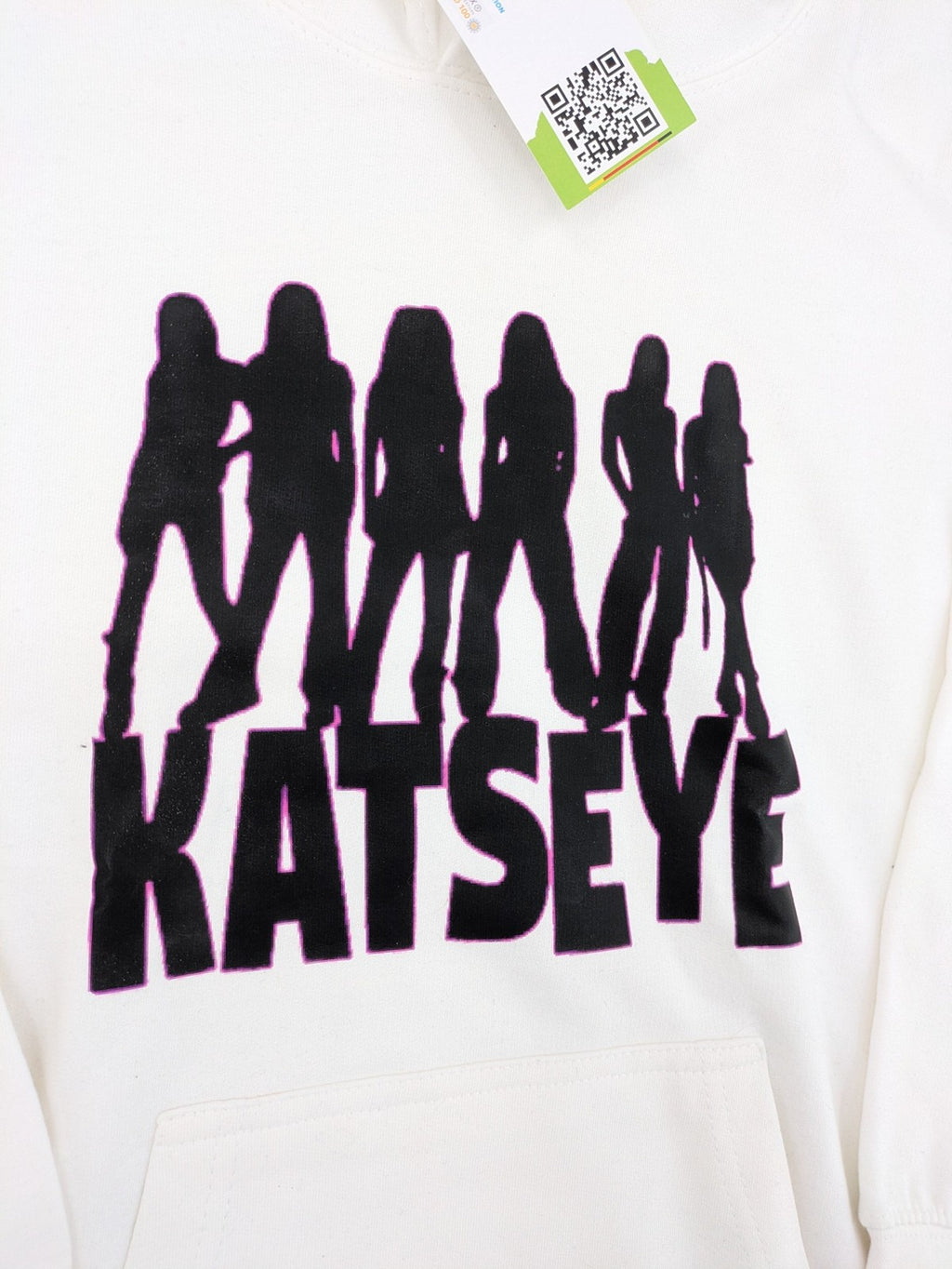 KATSEYE white zip-through hoodie with black silhouette graphic and logo, classic pullover style.