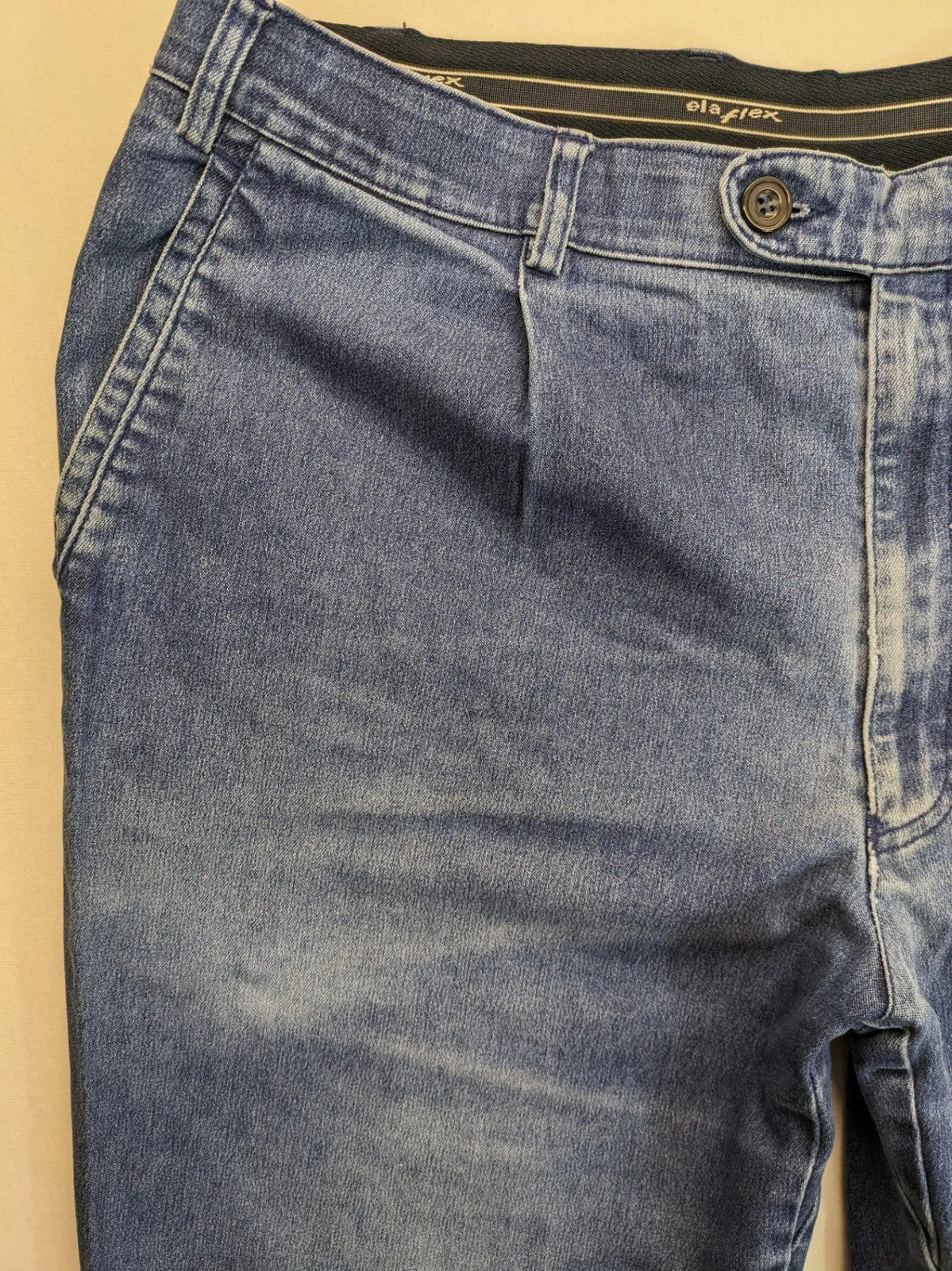 REI blue straight jeans with front pleats, zip fly, and buttoned back pockets.