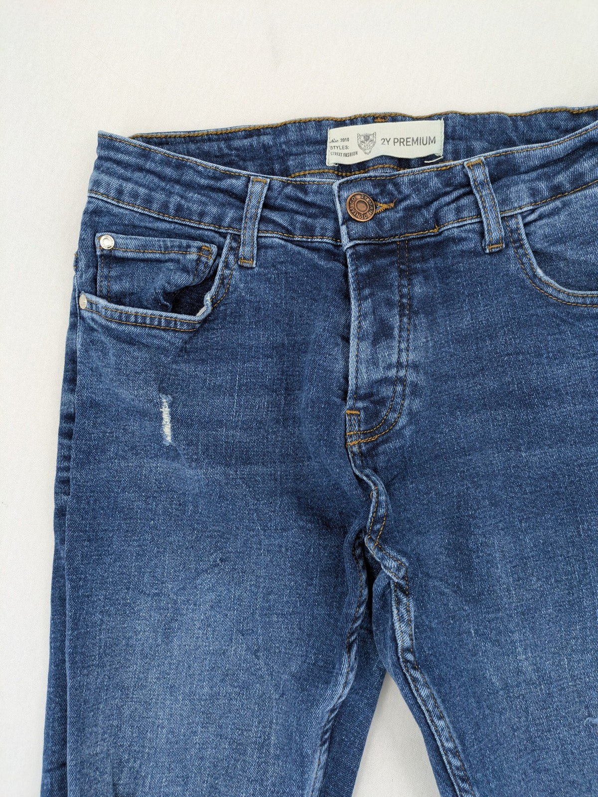 2Y Premium blue skinny jeans with distressed details and classic button fly.