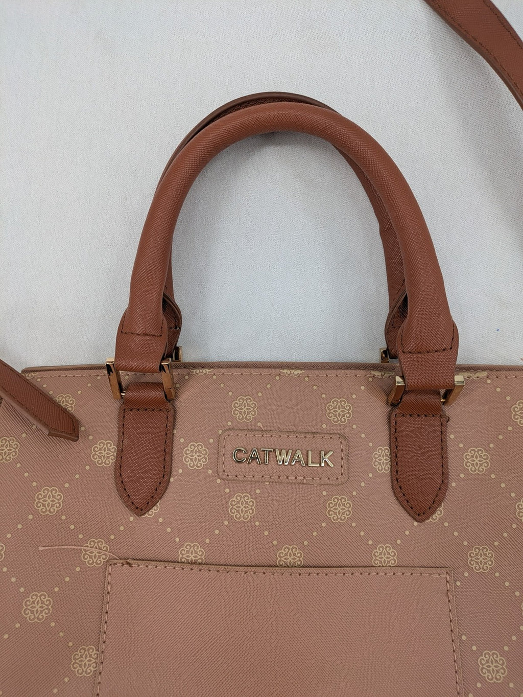 Catwalk gold handbag with pink and brown monogram pattern, adjustable shoulder strap.