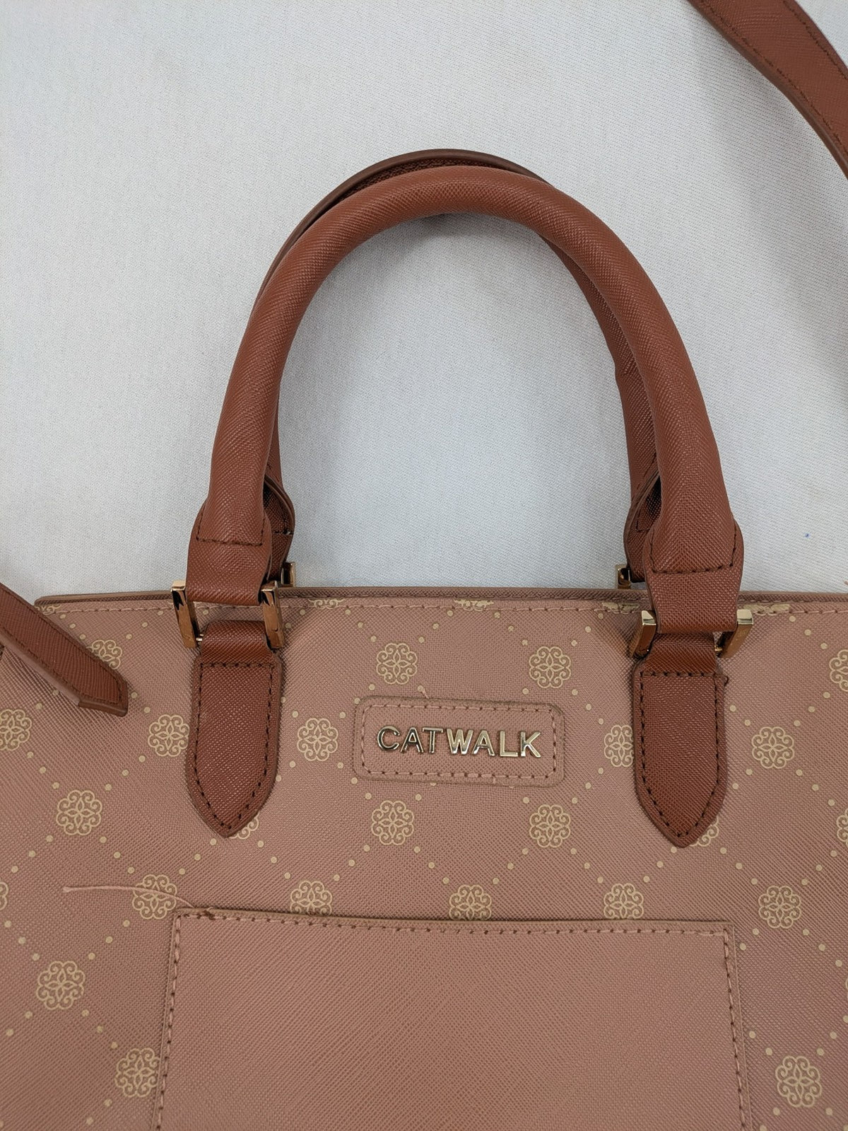 Catwalk gold handbag with pink and brown monogram pattern, adjustable shoulder strap.