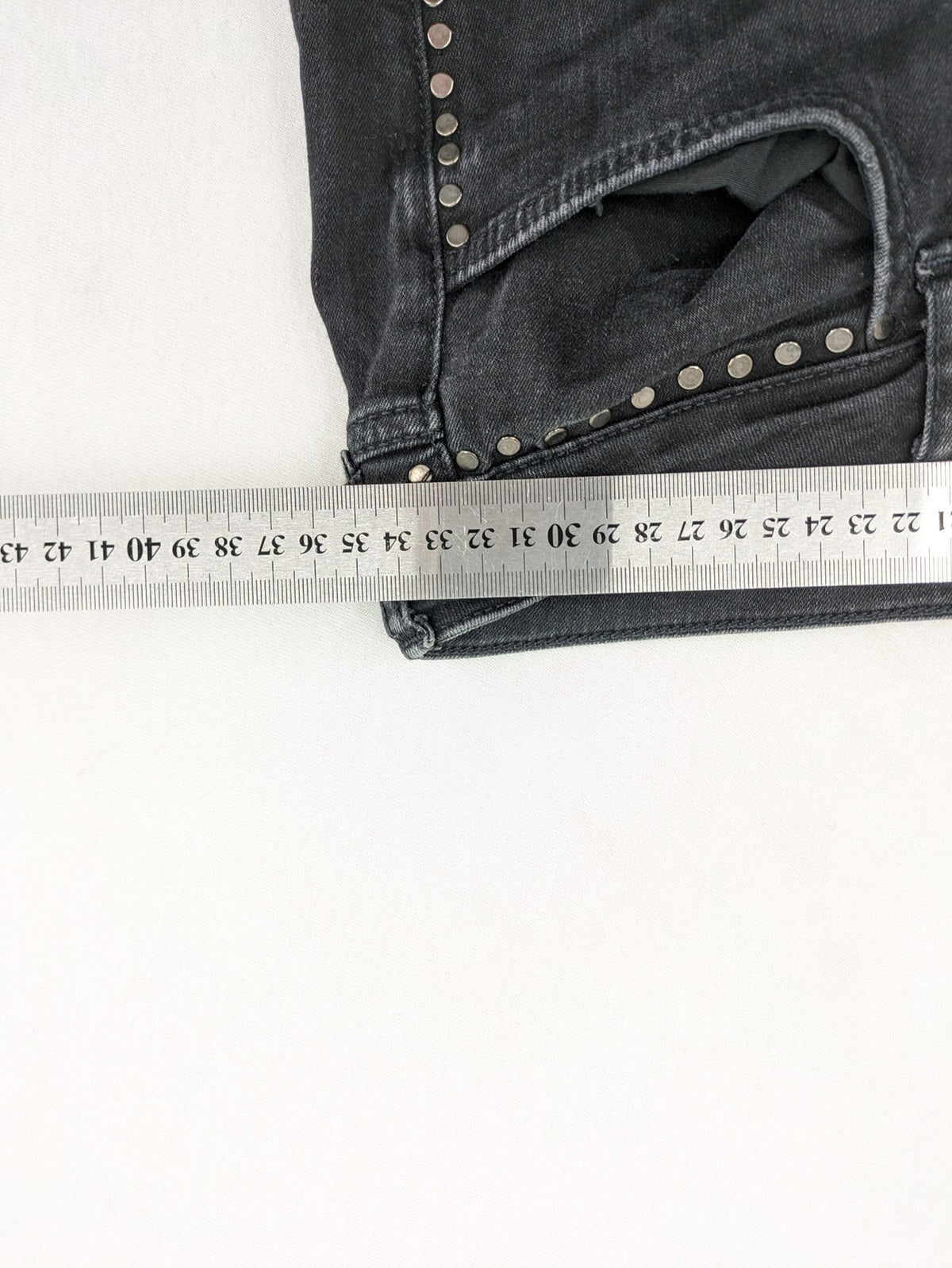 Zara Woman black skinny jeans with distressed details, silver studs, and frayed hem.