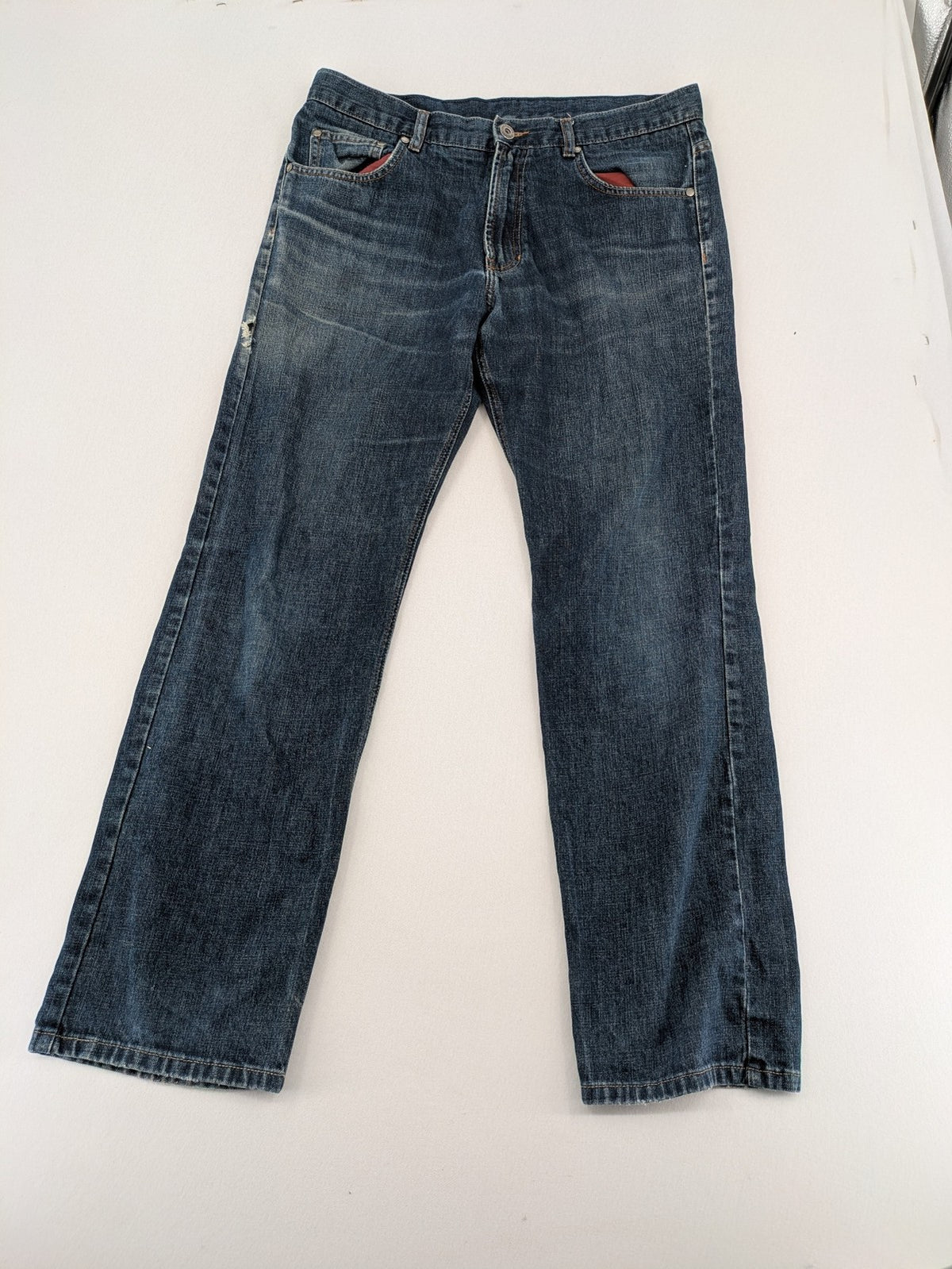 Indygo blue straight jeans 5-pocket style with subtle red pocket detail, cotton material.