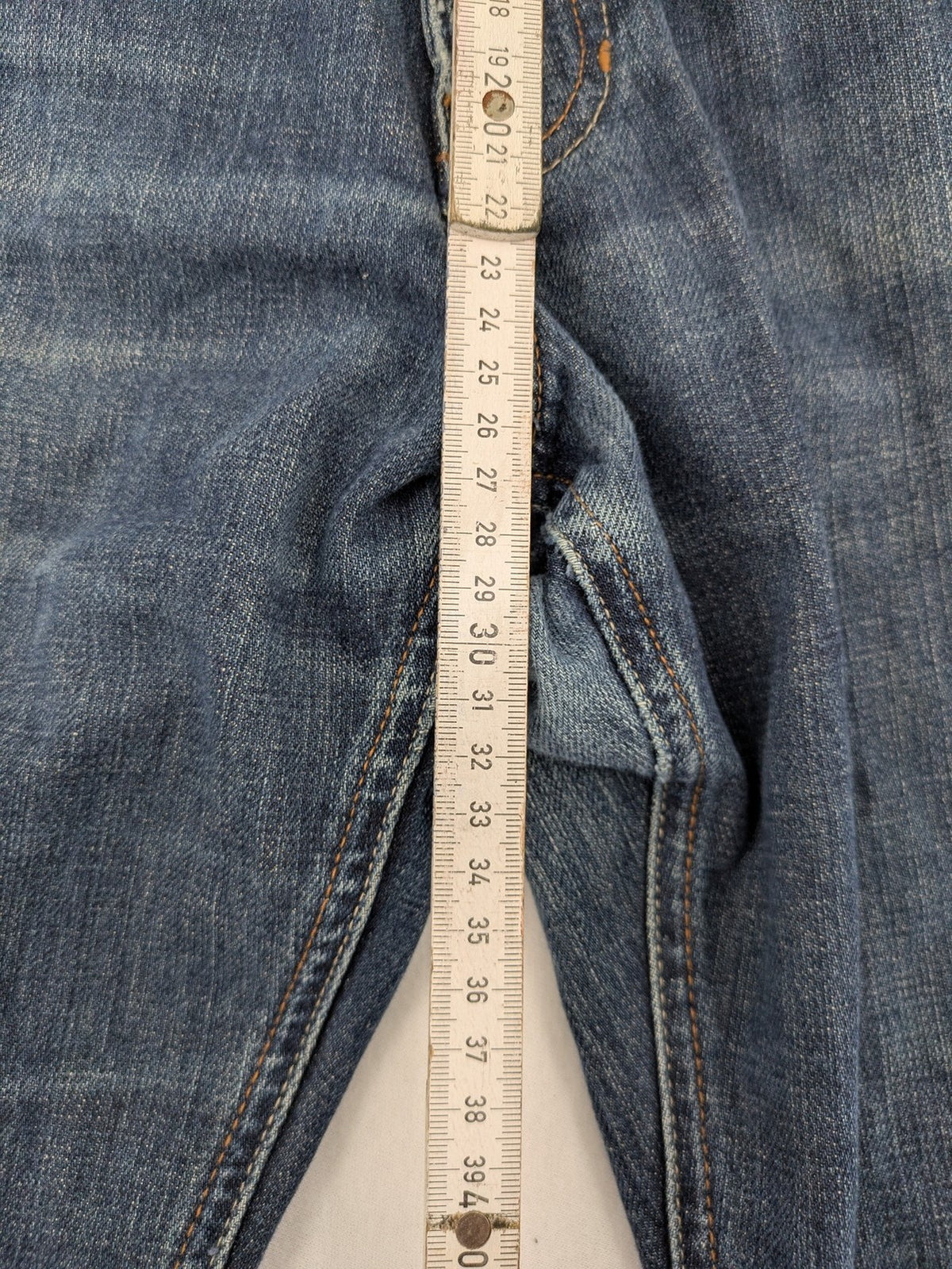 Indygo blue straight jeans 5-pocket style with subtle red pocket detail, cotton material.