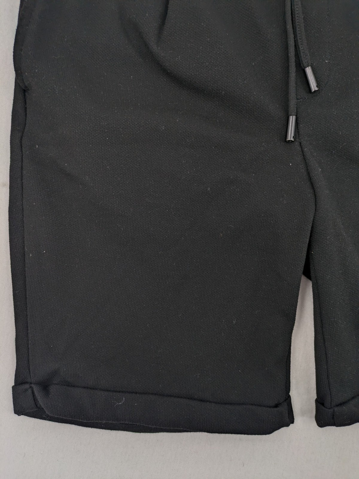 Zara black shorts with elastic drawstring, pleats, and rolled hem detail.