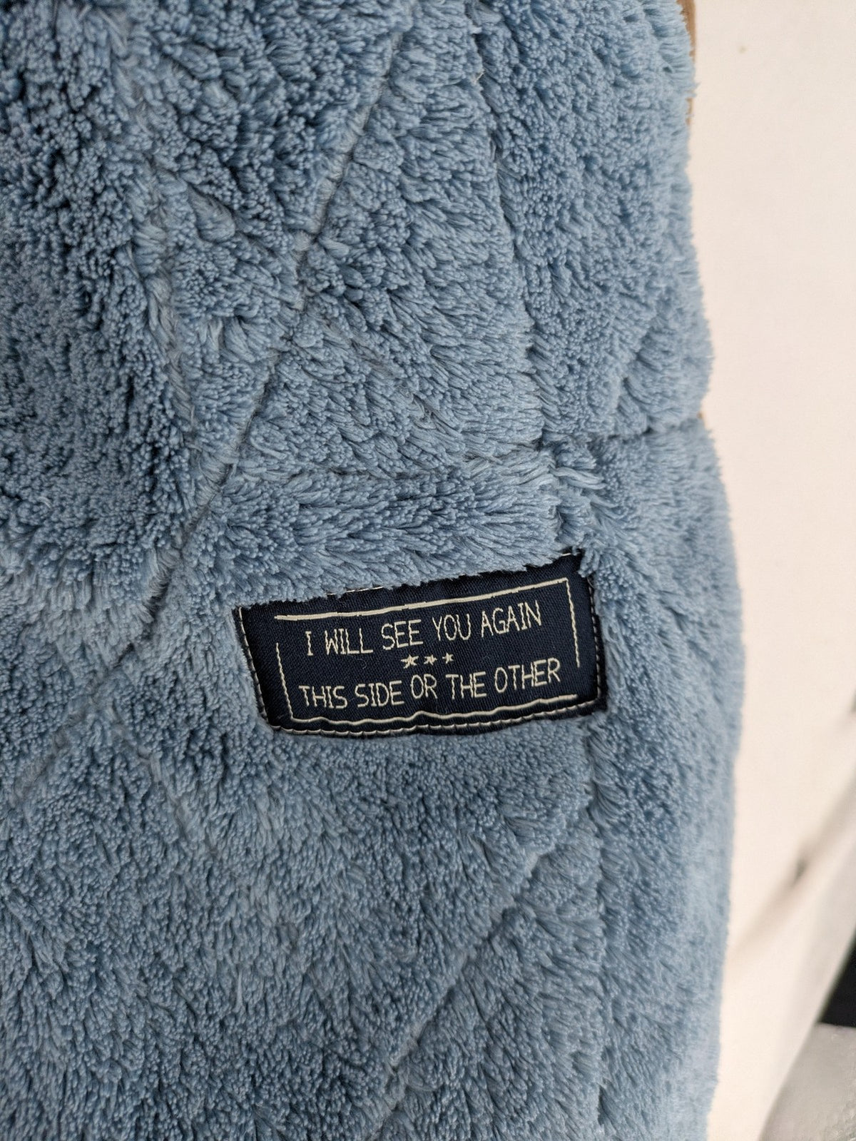 Naketano blue jacket with teddy fleece lining, hood, and leather appliqués.