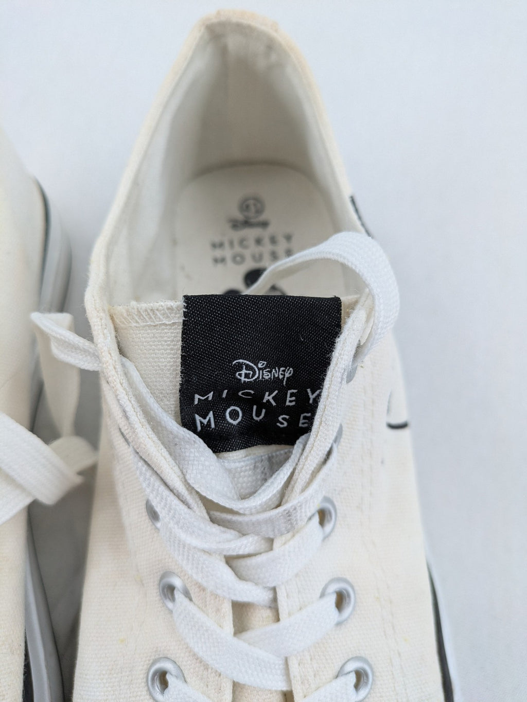Disney Mickey Mouse white canvas low top sneakers with iconic Mickey Mouse graphic.
