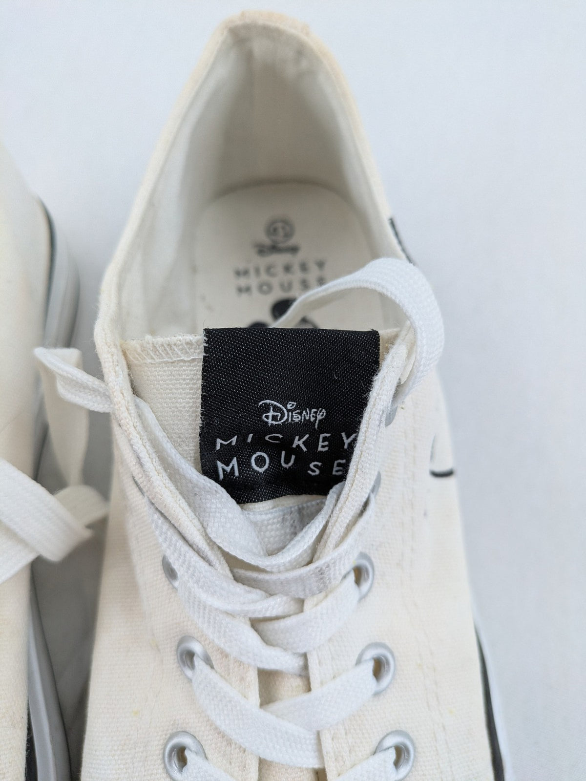 Disney Mickey Mouse white canvas low top sneakers with iconic Mickey Mouse graphic.