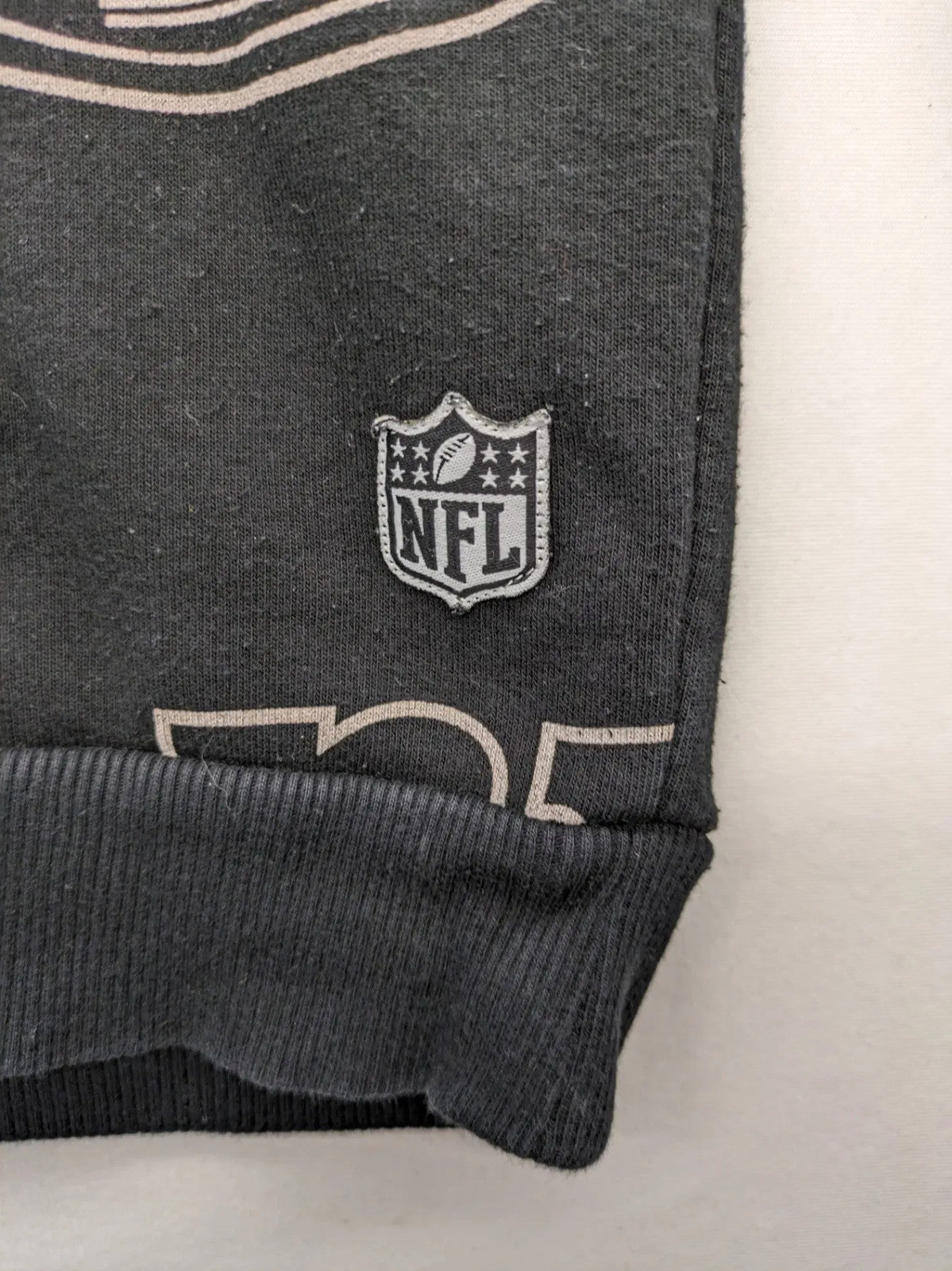 NFL black hoodie all-over team logo print, adjustable hood, cotton blend material.