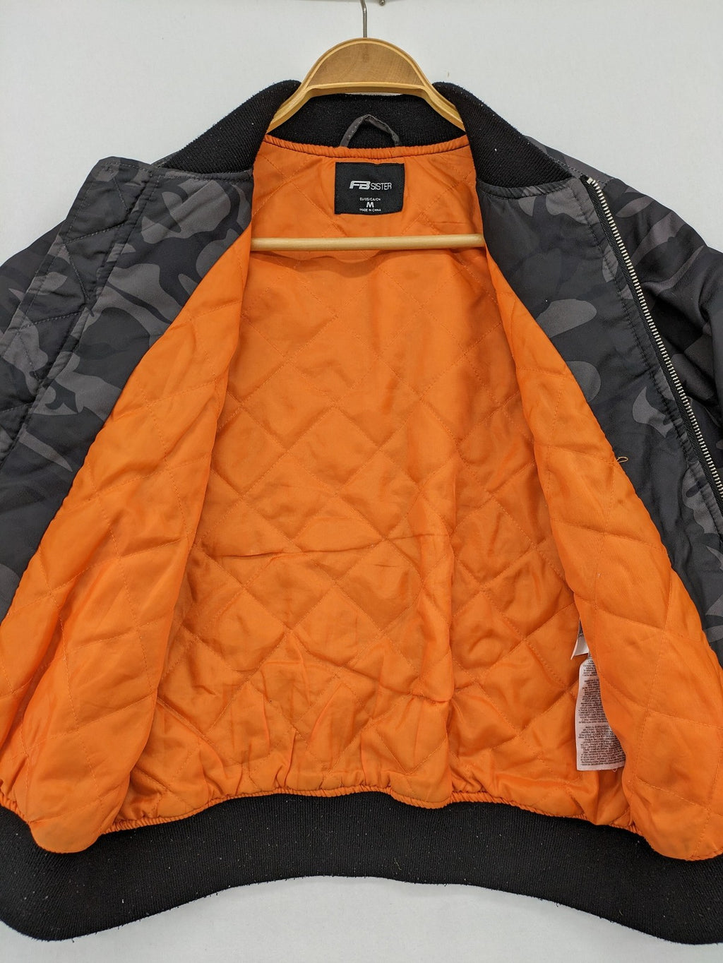 FB Sister orange bomber jacket with gray camouflage pattern and quilted lining.