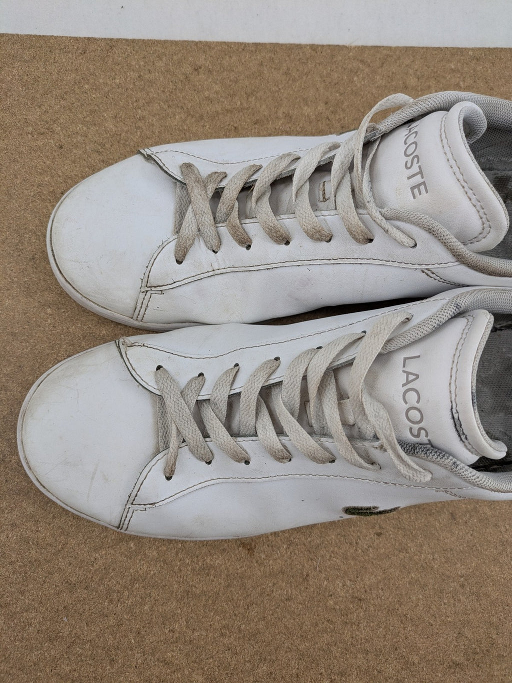 Lacoste cream low top sneakers with iconic crocodile logo and classic design.