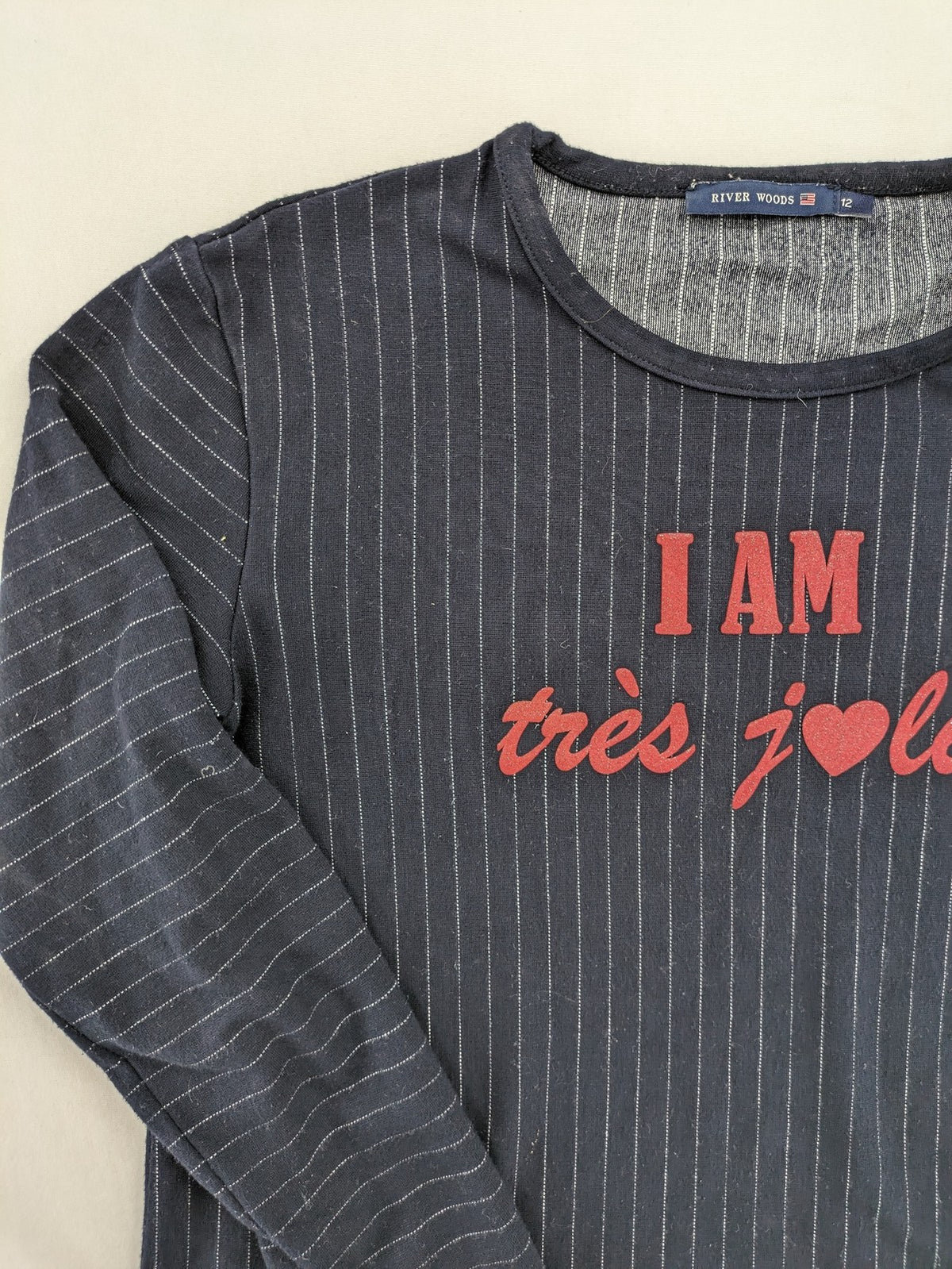 RIVER WOODS navy long sleeve top with white pinstripes and red "I AM très jolie" slogan.
