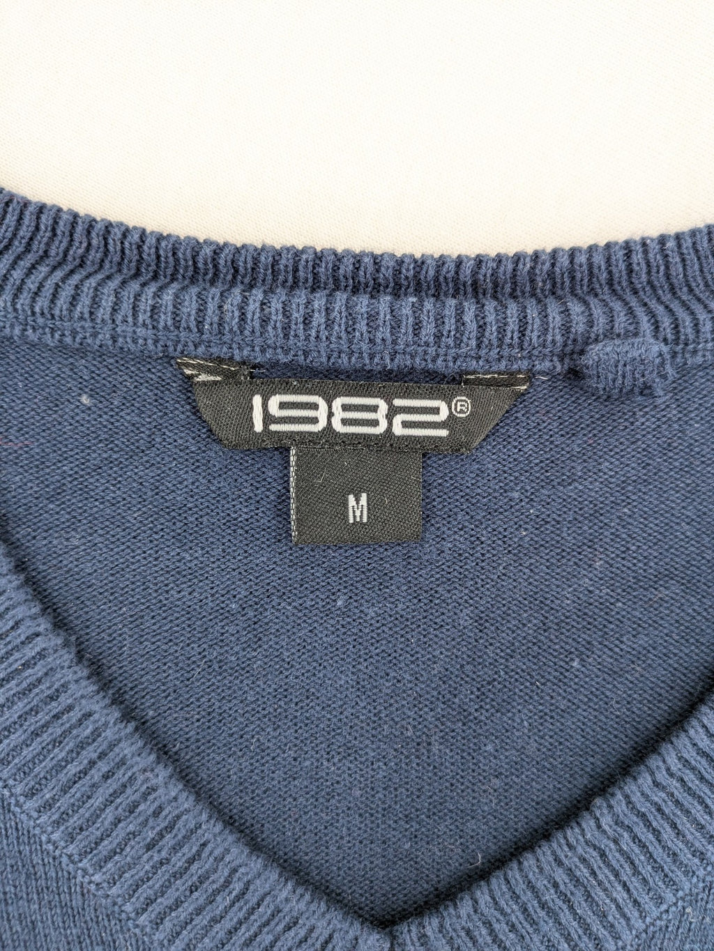 Queen blue knit jumper with embroidered crest logo, V-neck, 100% cotton.