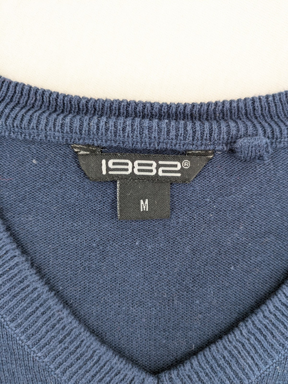 Queen blue knit jumper with embroidered crest logo, V-neck, 100% cotton.