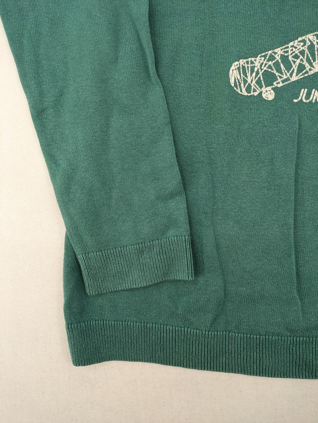 BESTies green turtle neck jumper with white skateboard graphic and ribbed cuffs.
