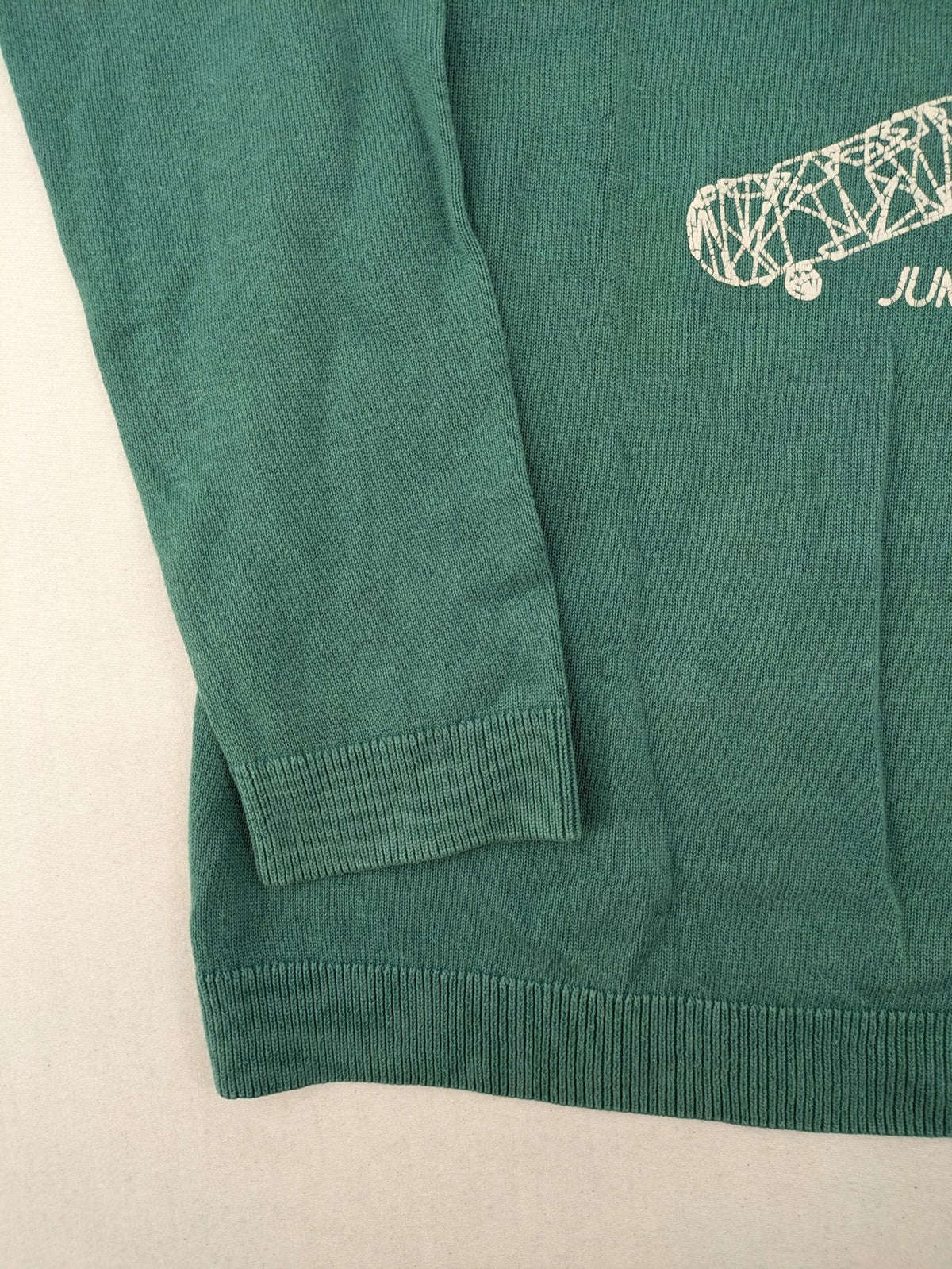 BESTies green turtle neck jumper with white skateboard graphic and ribbed cuffs.