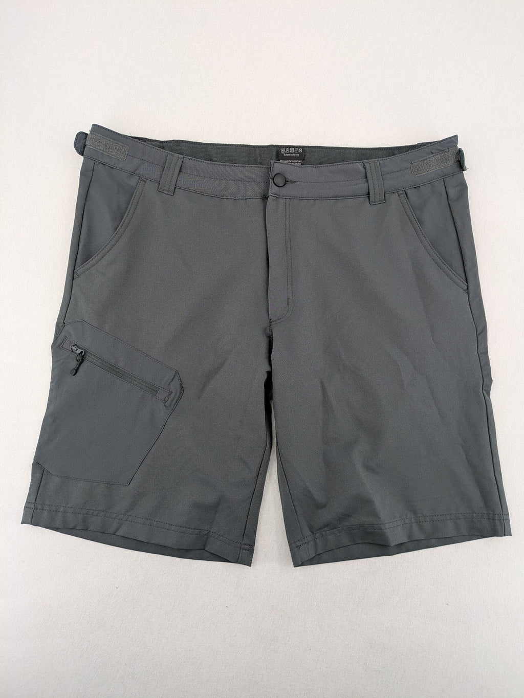 Outdoor grey functional shorts with adjustable velcro waistband and zippered leg pocket.