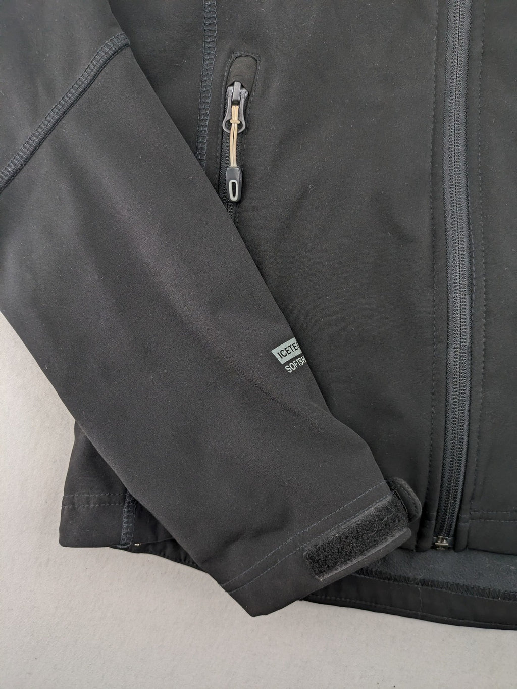 Icepeak black softshell jacket with fleece lining, adjustable hood, and zippered pockets.