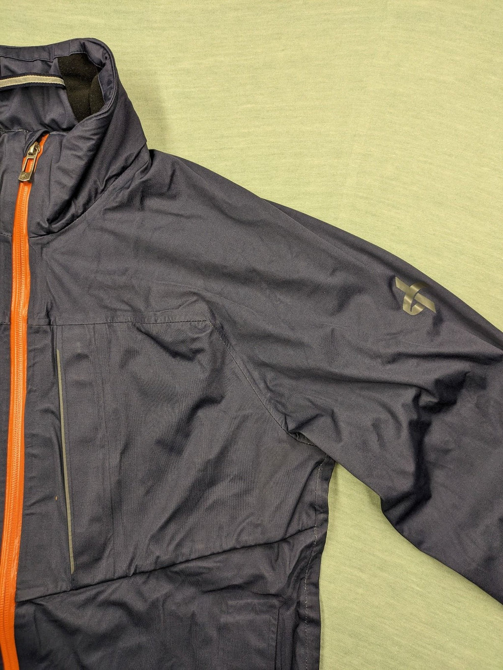 Cross Sportswear orange golf jacket with full zip, high collar, and contrast zipper details.