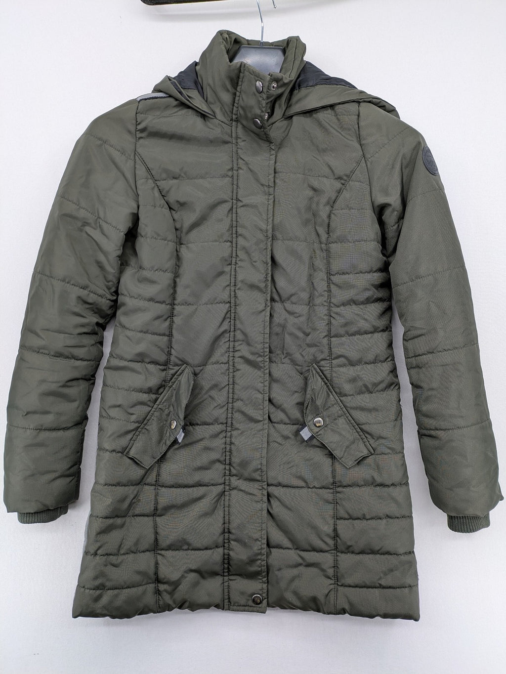 Vero Moda green puffer coat with quilted design and hood, featuring zipper and button closure.