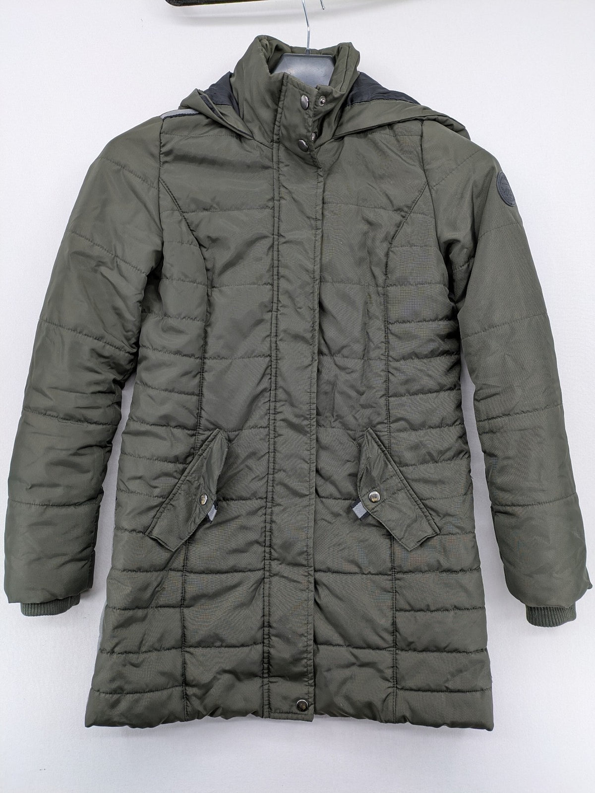 Vero Moda green puffer coat with quilted design and hood, featuring zipper and button closure.