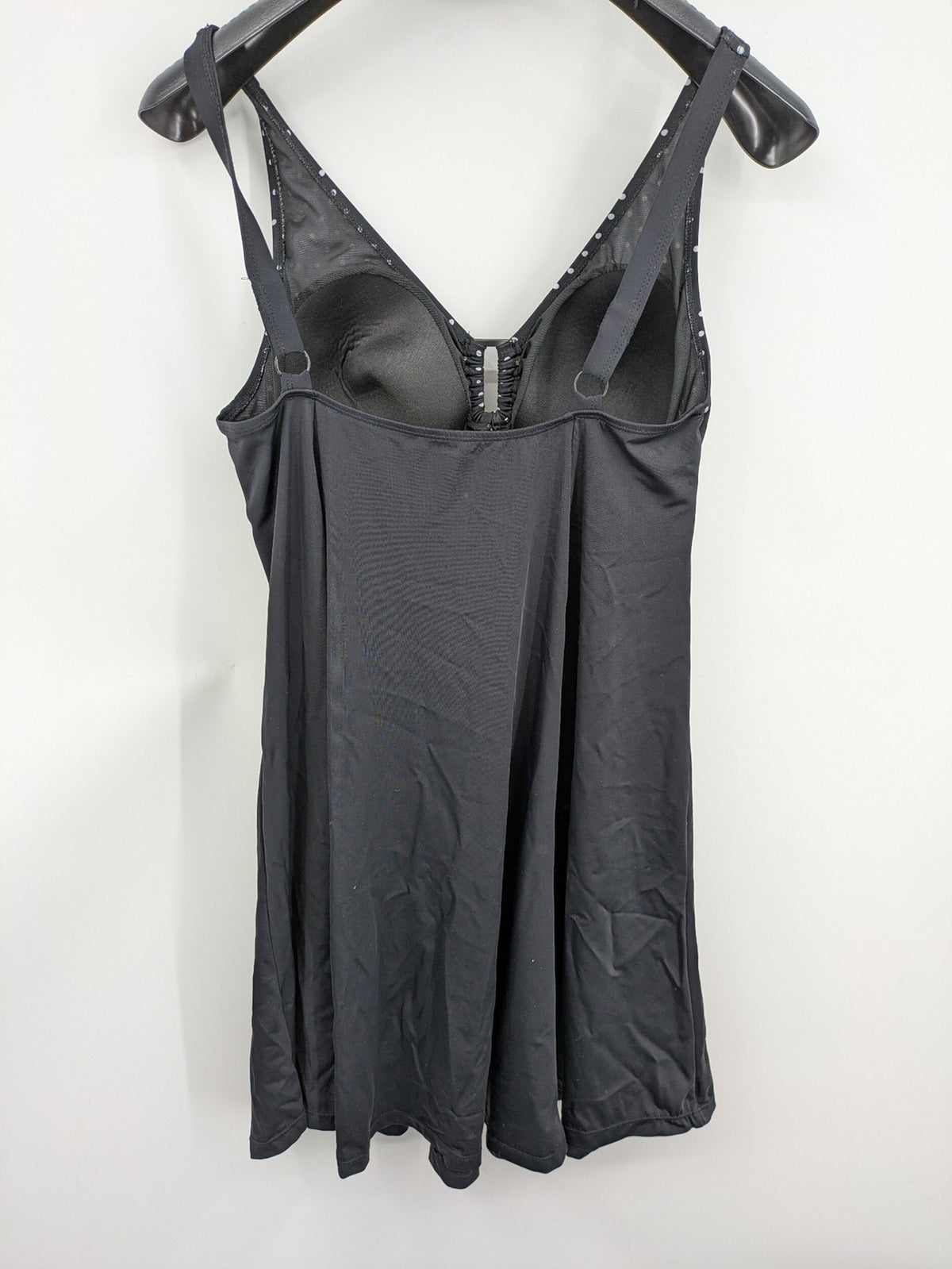 Elegante black swimsuit with white polka dots, V-neck, adjustable straps, and padded cups.