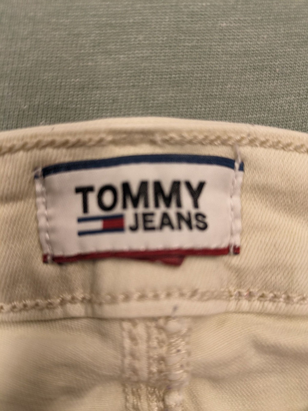 Tommy Jeans beige high rise skinny ankle jeans with logo patch and stretch fabric.