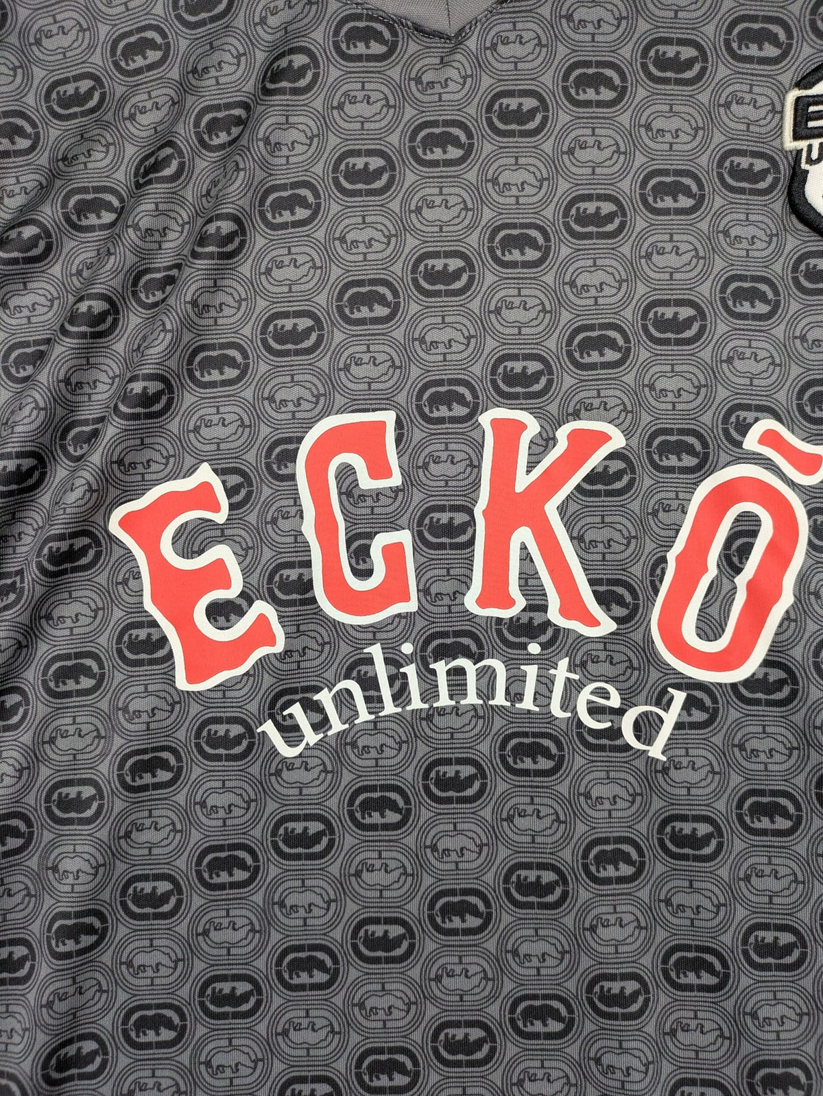 Ecko Unltd. grey soccer uniform V-neck with all-over logo print and embroidered FC patch.
