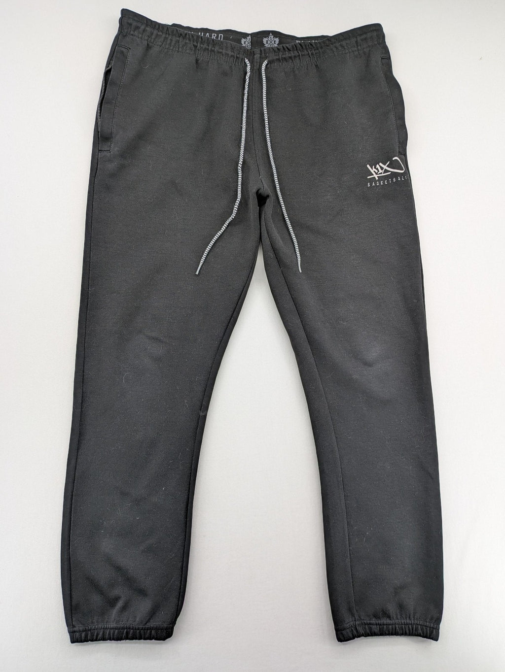 K1X grey joggers with white basketball logo, elastic waistband, and cuffed ankles.