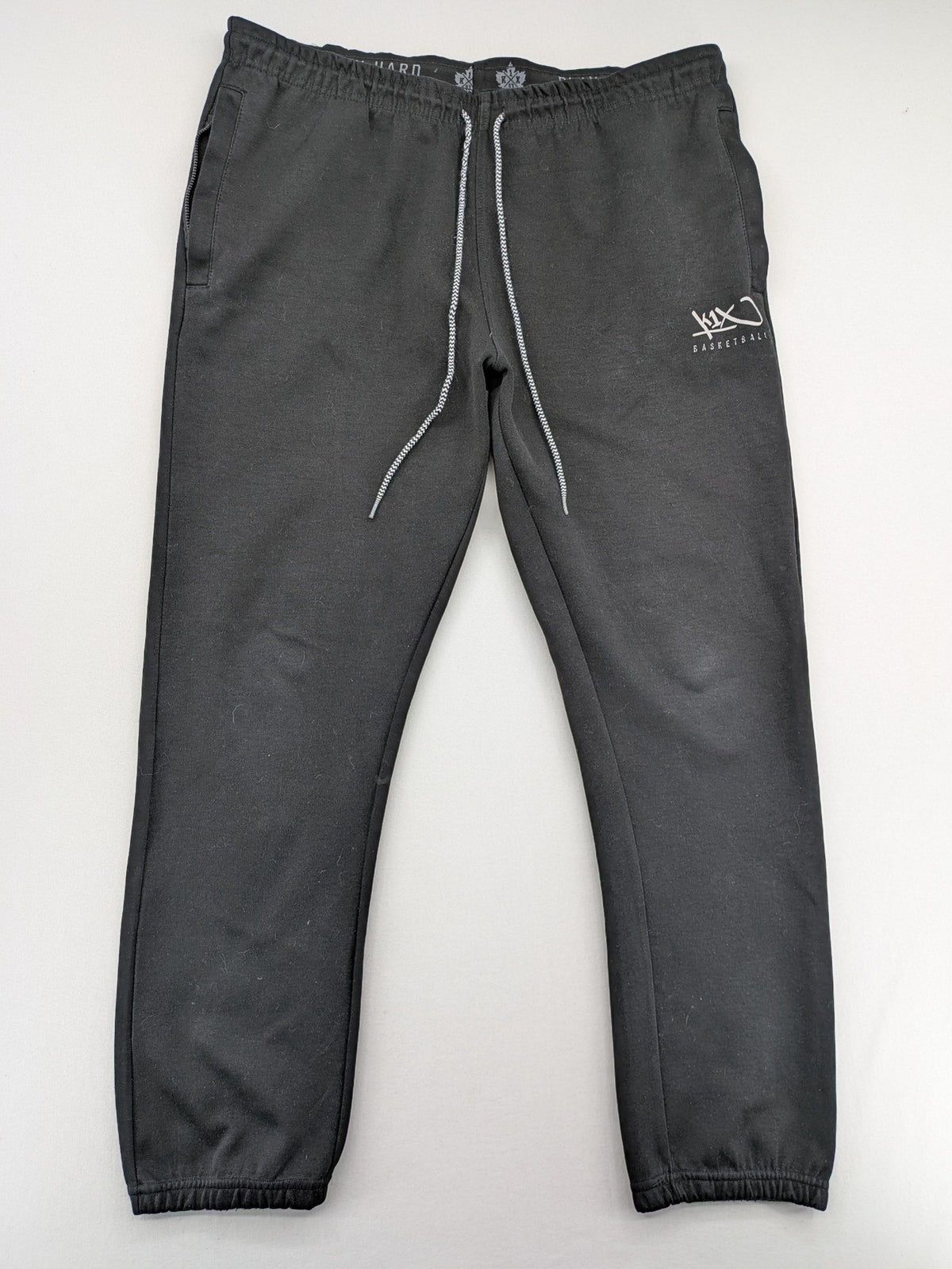 K1X grey joggers with white basketball logo, elastic waistband, and cuffed ankles.
