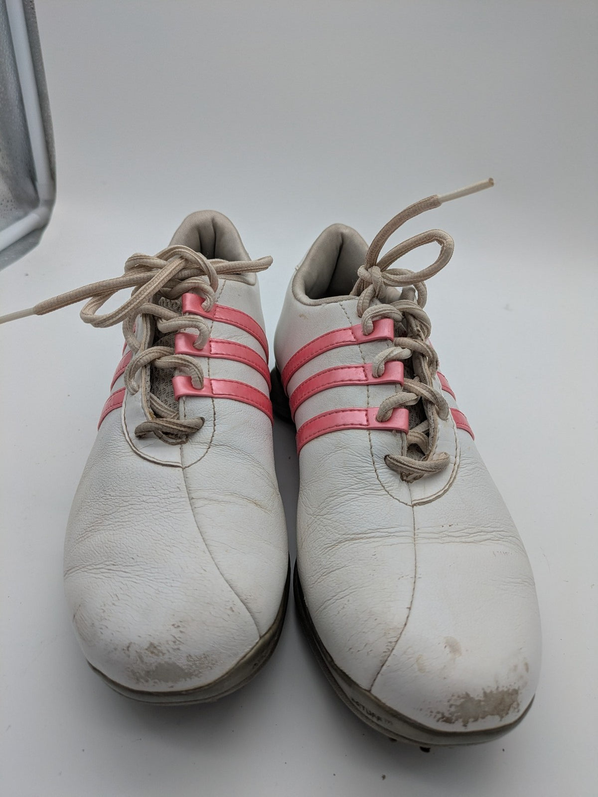 Adidas white golf shoes with pink stripes, Thintech and TRAXION technology, stylish design.