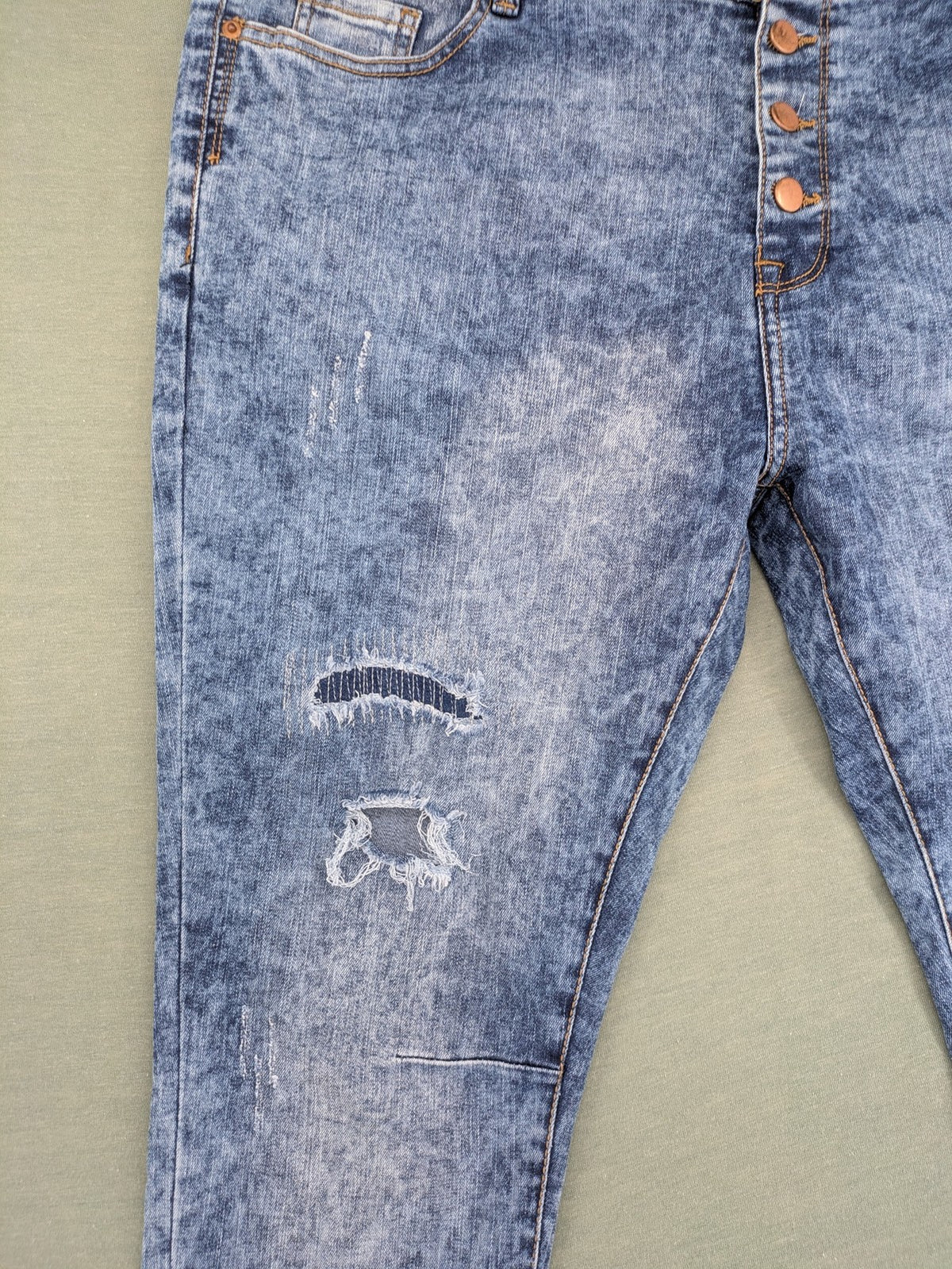 Janina blue slim fit jeans with acid wash, destroyed details, and button fly.