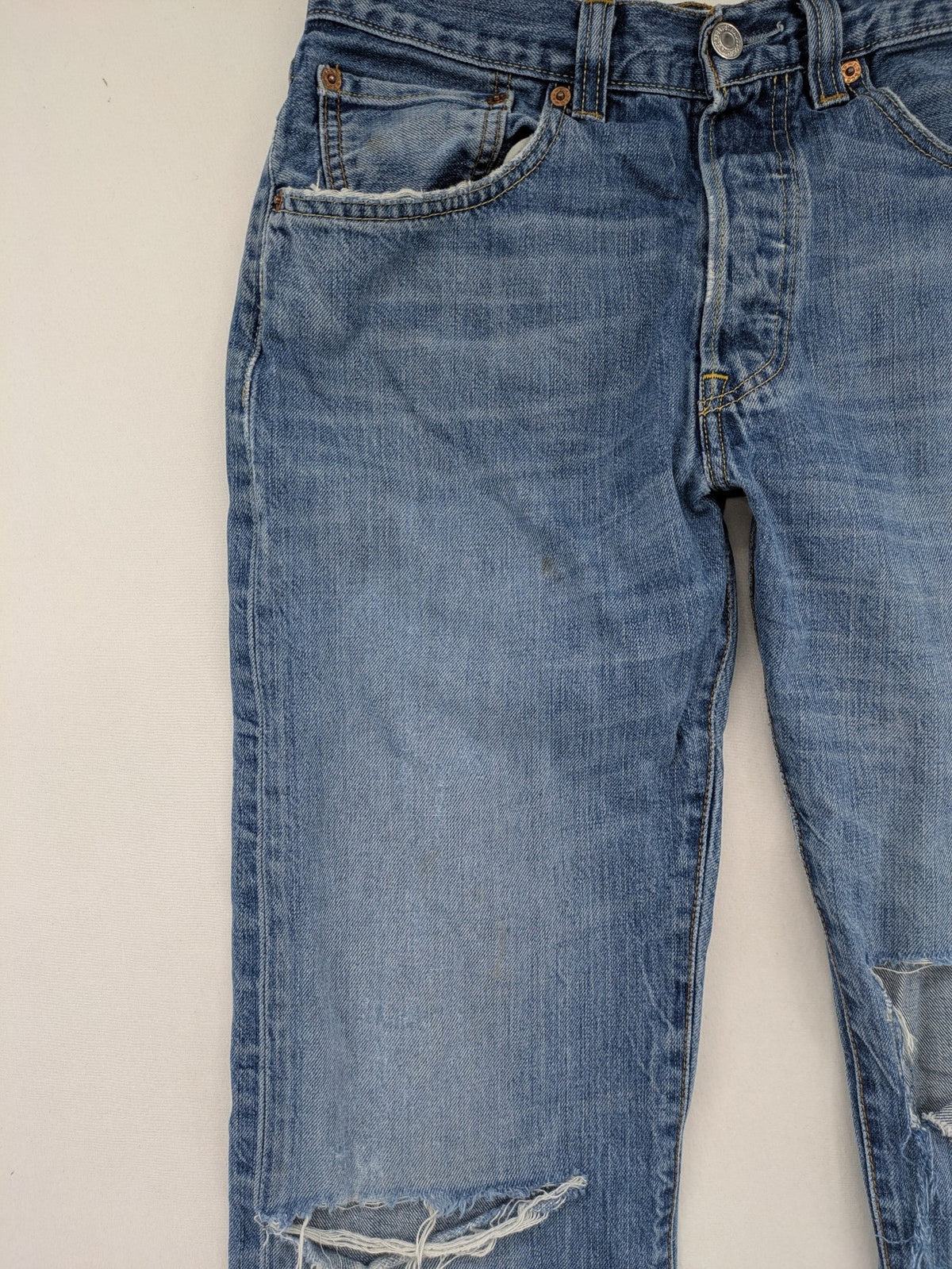 Levi's blue straight jeans with button-fly and distressed knee rips.