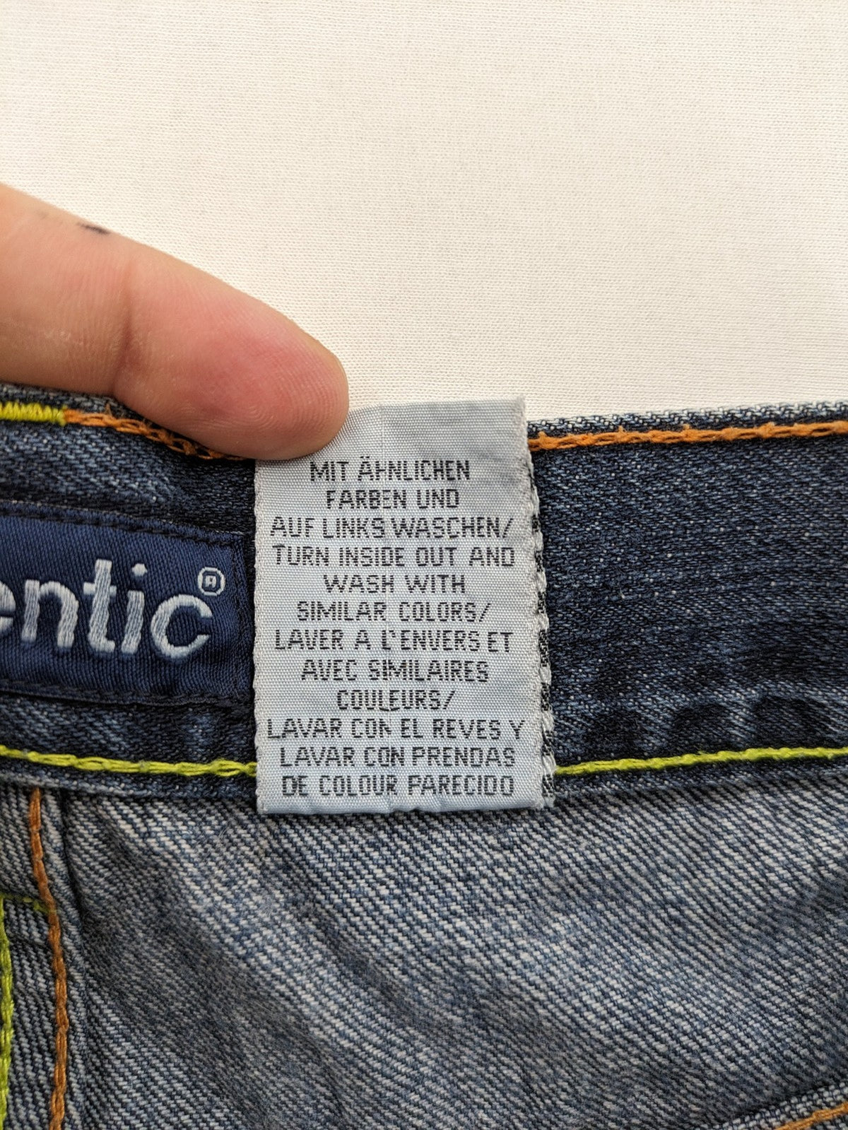 Identic orange straight jeans with paneled design and contrasting yellow stitching.