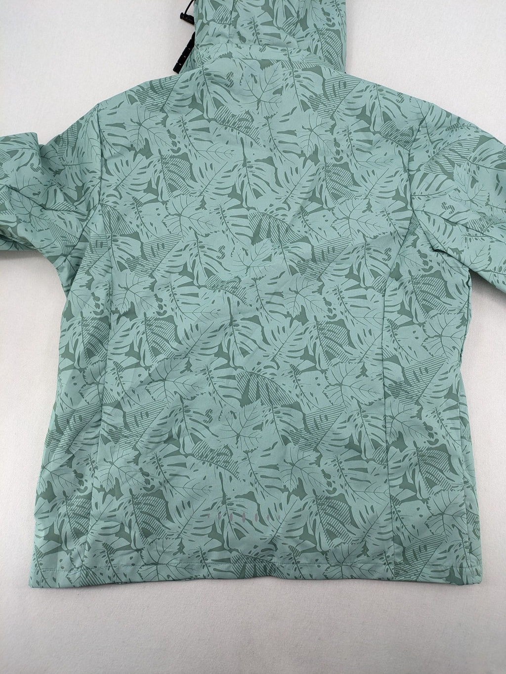 Outdoor green jacket with allover leaf print, adjustable hood, and front zipper.