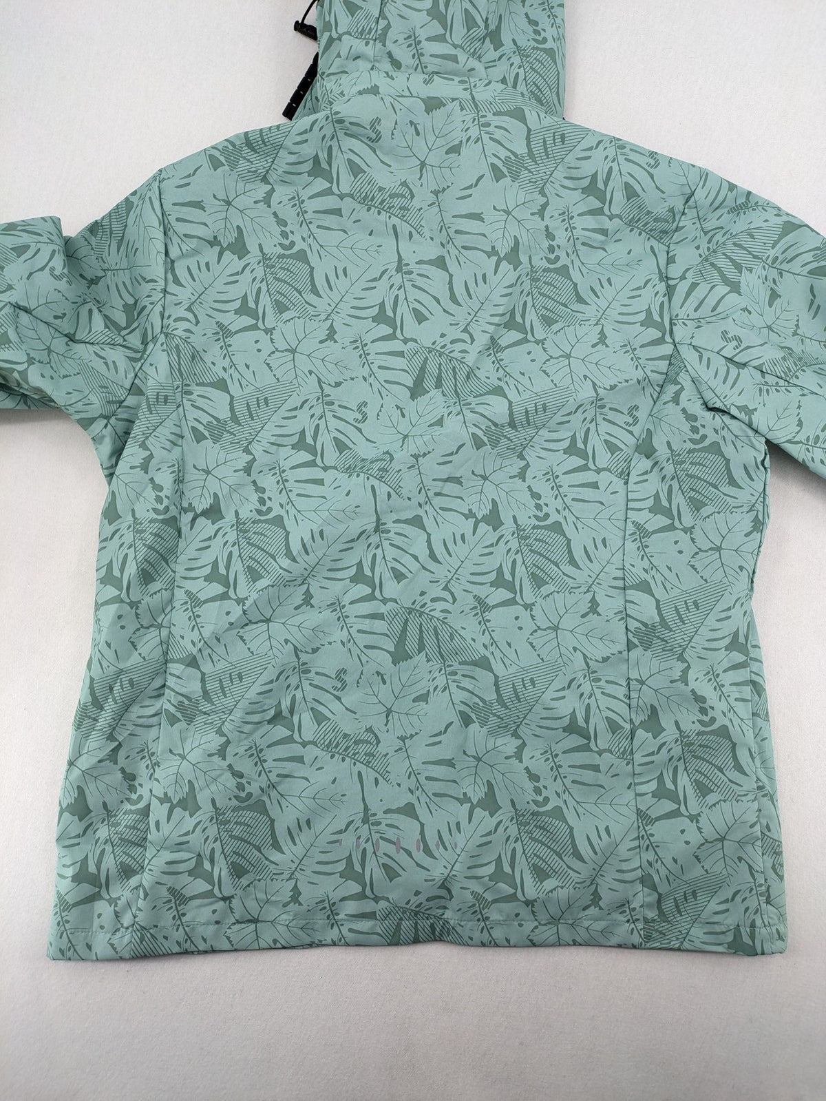 Outdoor green jacket with allover leaf print, adjustable hood, and front zipper.