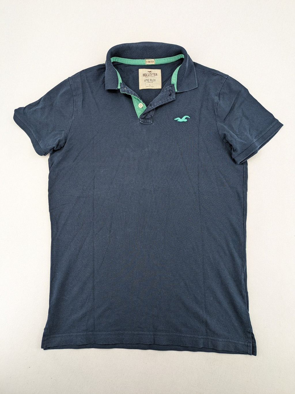 Hollister polo shirt navy blue with embroidered seagull logo and green trim.
