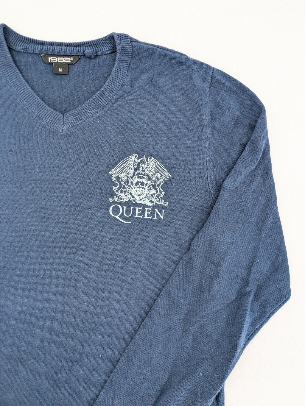 Queen blue knit jumper with embroidered crest logo, V-neck, 100% cotton.