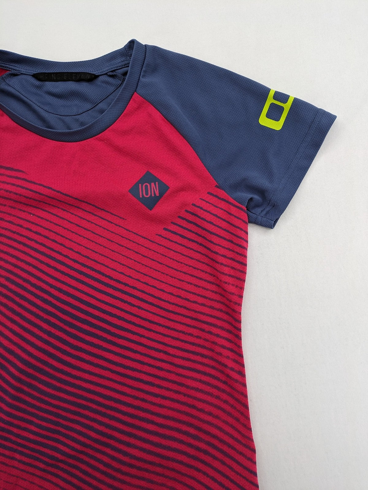 Muster blue and red short-sleeve functional shirt with dynamic wave pattern and raglan sleeves.