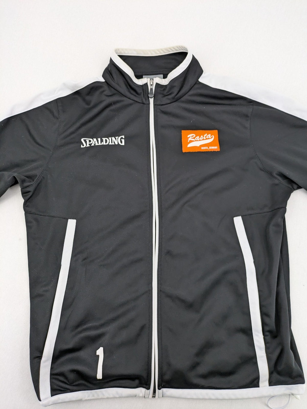 Spalding black training jacket with orange and white accents, Rasta Vechta logo, zip front.