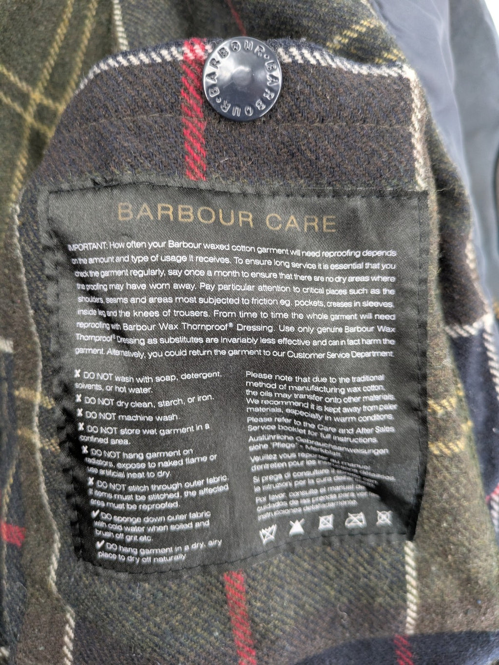 Barbour navy wax jacket with quilted lining and leather elbow patches, tartan interior.