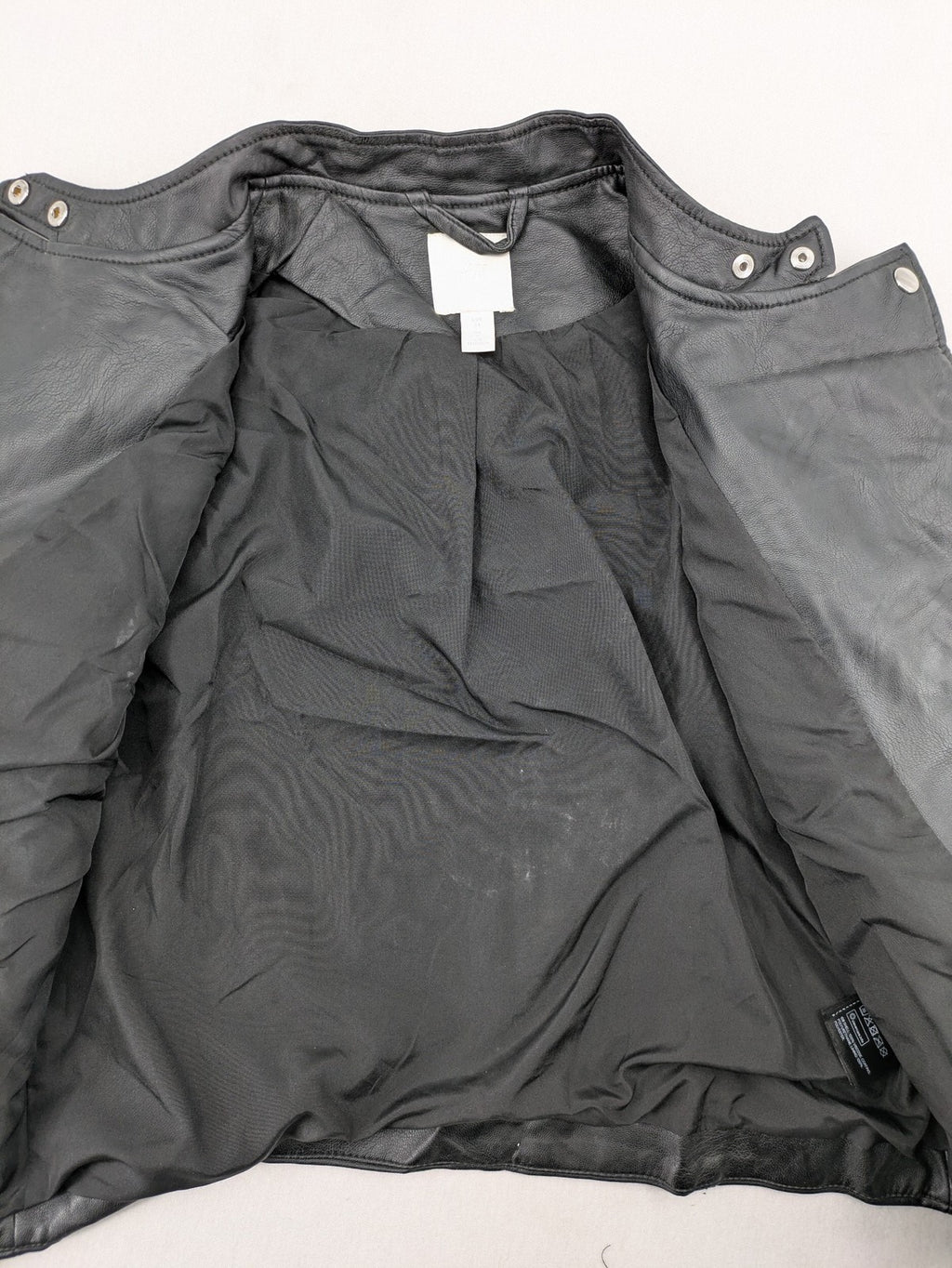 H&M black biker jacket with silver zippers, shoulder flaps, and snap-button details.