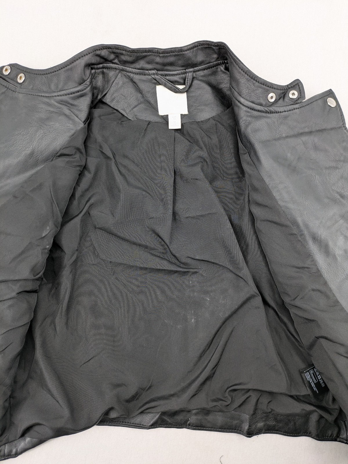 H&M black biker jacket with silver zippers, shoulder flaps, and snap-button details.