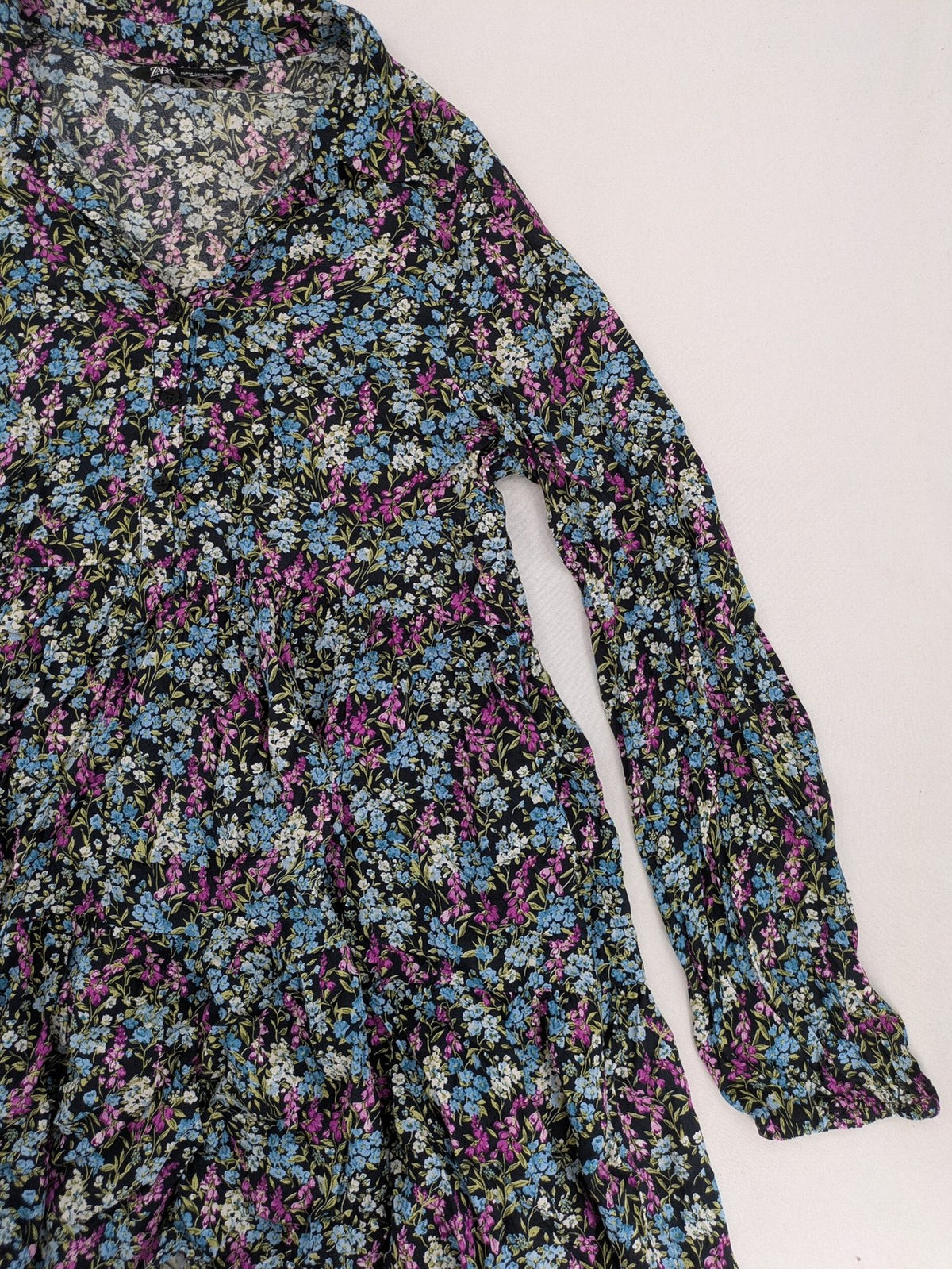 Zara multi-coloured floral mini dress with classic collar and button placket on black background.
