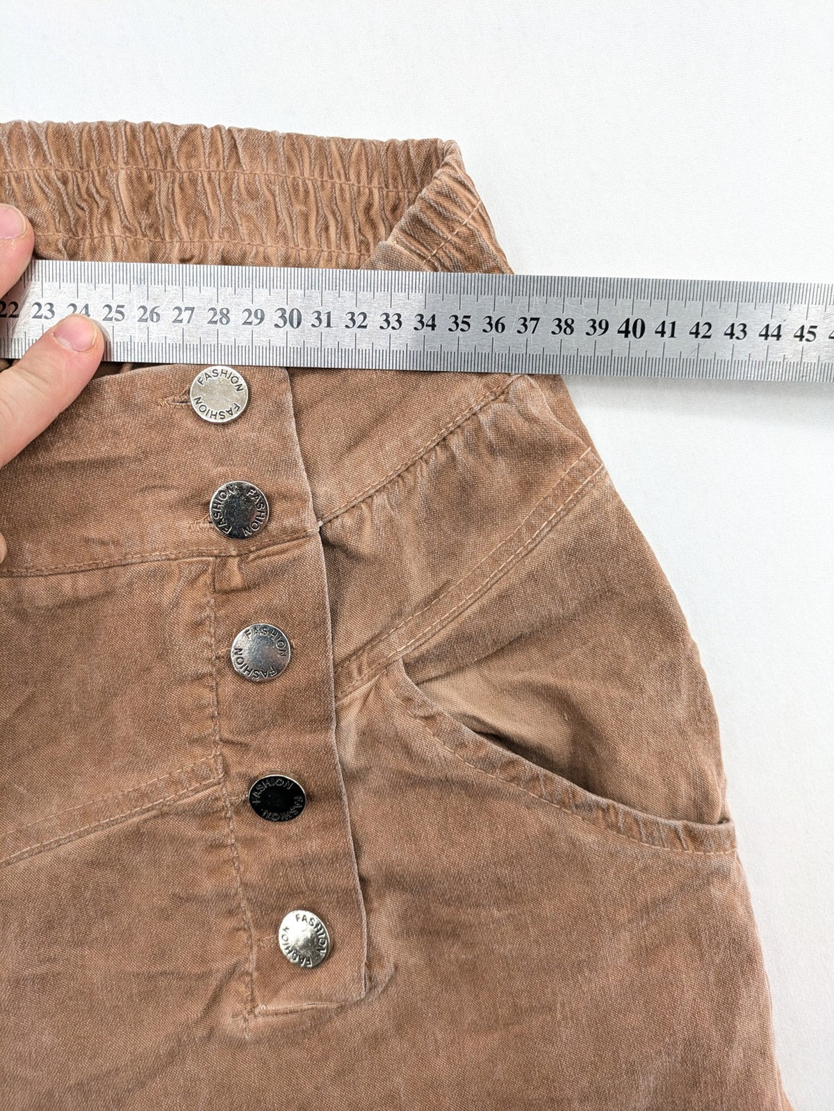 TREDY brown high-waist pants with decorative button placket and elastic waistband, soft knit texture.