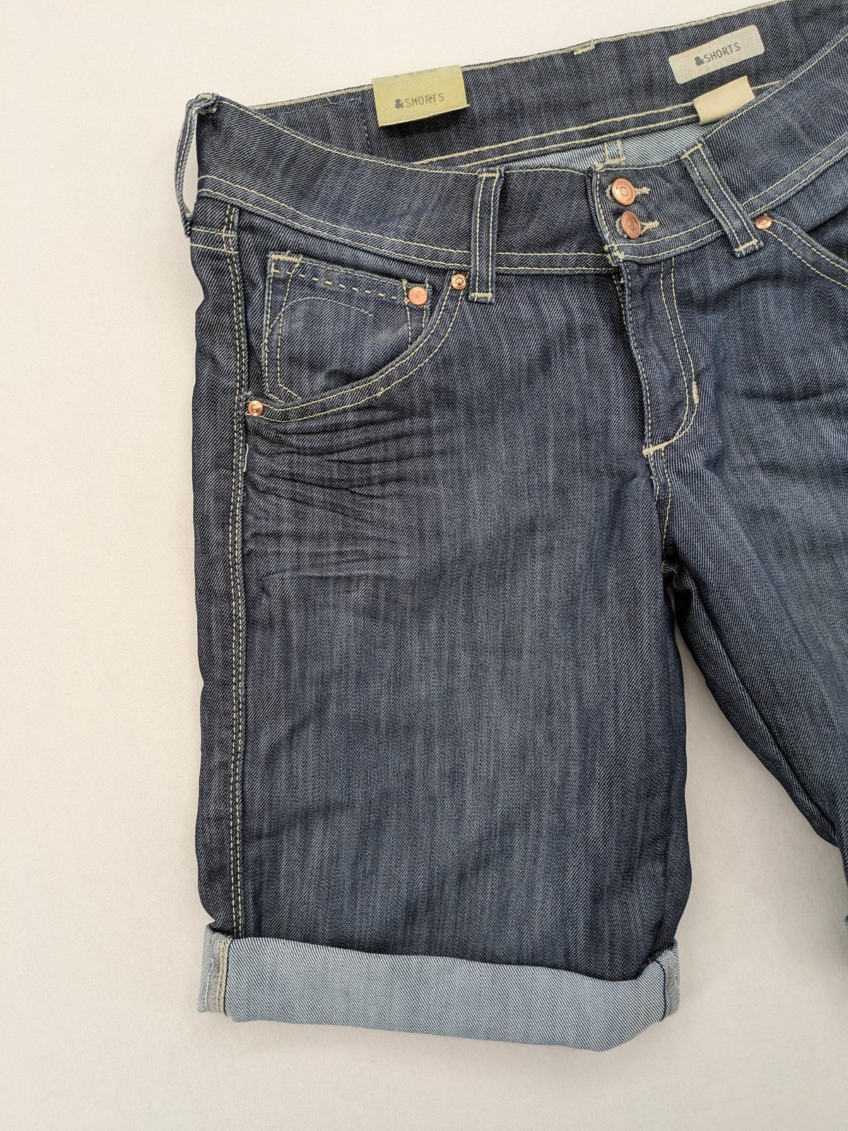 H&M blue denim shorts with rolled cuffs and back patch pockets, mid-rise fit.