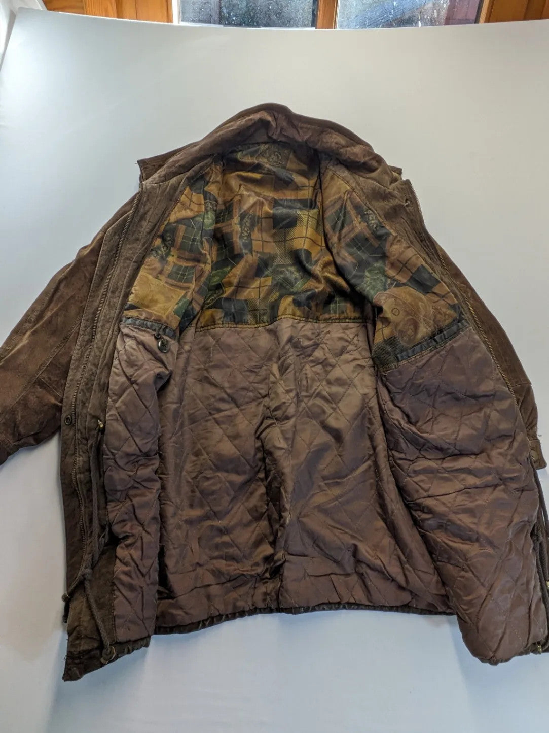 Vintage brown leather jacket with graphic lining, zip closure, and button placket.