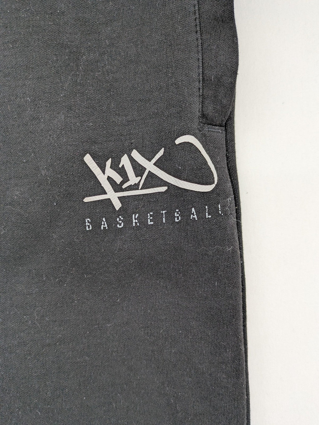 K1X grey joggers with white basketball logo, elastic waistband, and cuffed ankles.