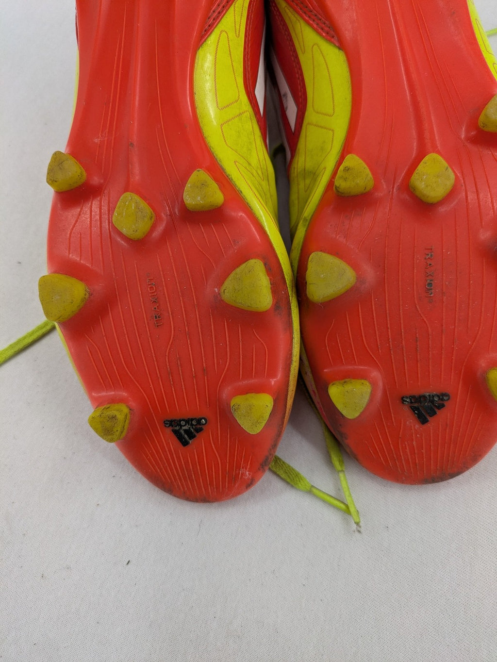 Adidas F50 soccer shoes red and yellow with three-stripe logo and lightweight synthetic material.