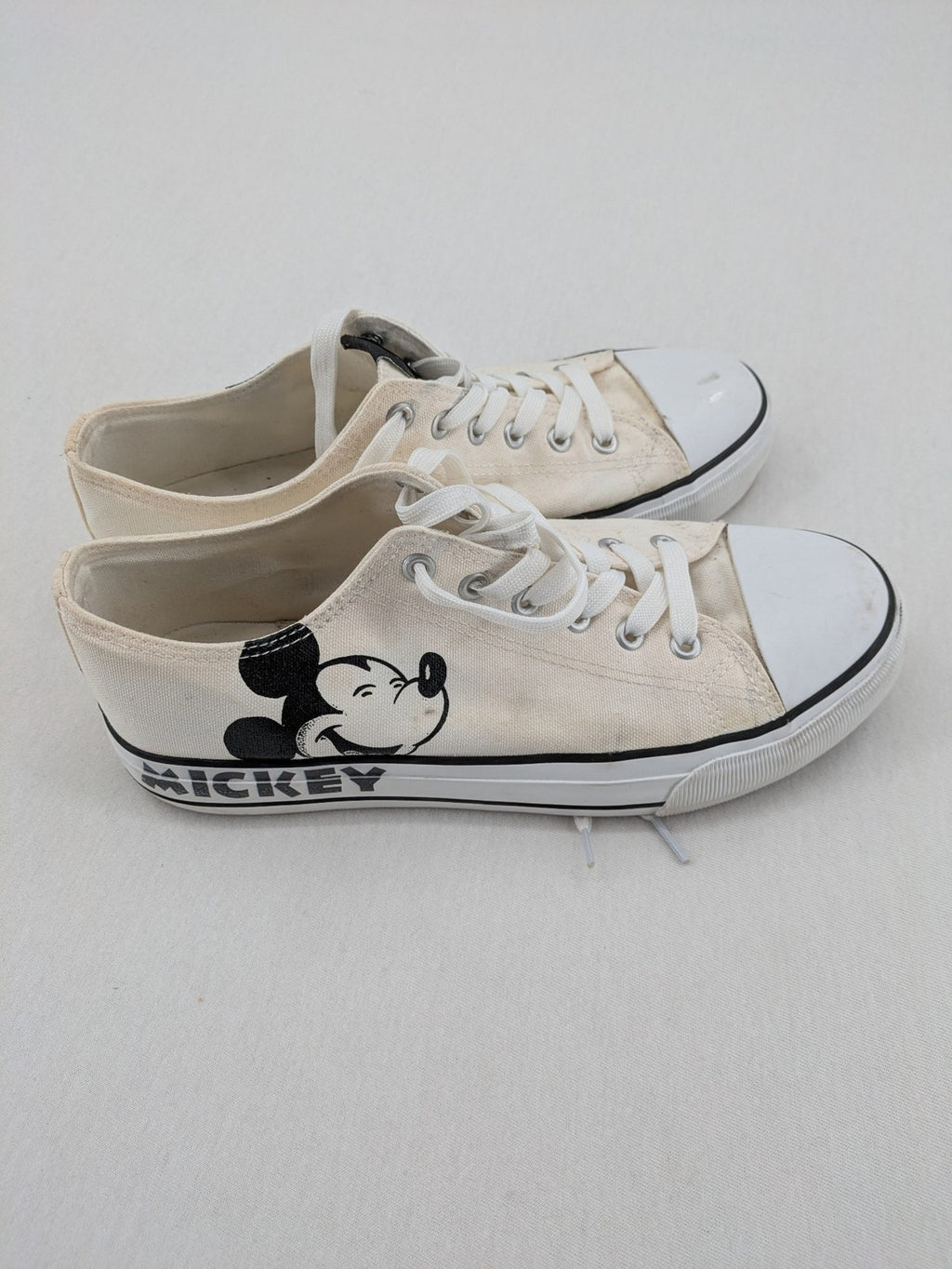 Disney Mickey Mouse white canvas low top sneakers with iconic Mickey Mouse graphic.